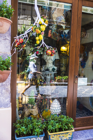 Cefalu, Italy - August 8, 2017: Souvenir shop with a woman walking reflected in the old town of the historic village of Cefalu in Sicily, Italyのeditorial素材