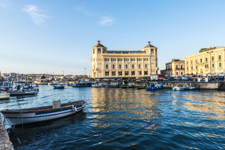 Fishing and recreational boats docked at the marina with classic buildings around in the historic city of Siracusa in Sicily, Italyの写真素材