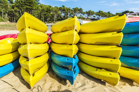 Heap of yellow and blue kayaks or boats of plastic on a beach of Palamos, Costa Brava, Girona, Catalonia, Spainの写真素材
