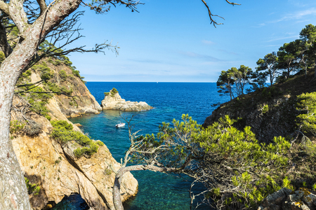 Yacht next to a cliff with a cave in crystal clear waters of the Mediterranean sea in Palamos, Costa Brava, Girona, Catalonia, Spainの写真素材