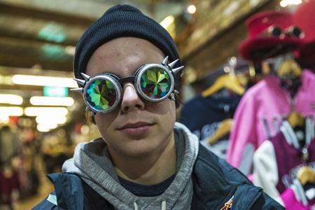 A teenage boy in a Gothic sunglasses with diffracted lens or Kaleidoscope in a fashion shop of Camden Lock Market or Camden Town in London, England, United Kingdomの写真素材