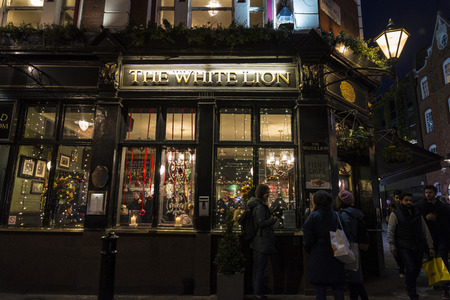 London, United Kingdom - January 1, 2017: Typical english pub called the White Lyon with people around at night in London, England, United Kingdomのeditorial素材