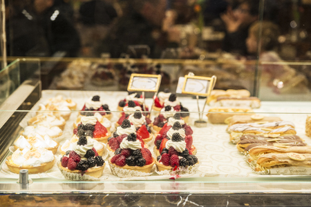 London, United Kingdom - January 3, 2018: Cream and raspberry cakes in a candy store with people around in London, England, United Kingdomのeditorial素材