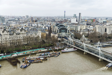 Hungerford Bridge, also called Charing Cross Bridge and the Charing Cross train station over the River Thames with boats sailing and moored in London, England, United Kingdomのeditorial素材
