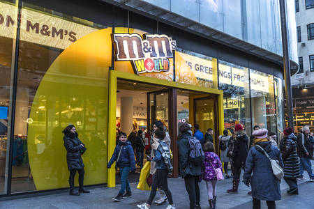 London, United Kingdom - January 4, 2018: Logo of M&M's shop, famous by its colorful button-shaped chocolates, with people around in London in England, United Kingdomのeditorial素材