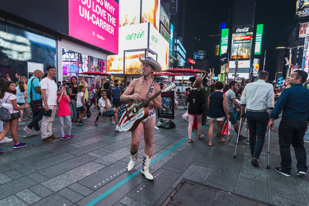 New York City, USA - July 30, 2018: Cowboy in his underpants and with a guitar on Times Square at night with people around and large advertising screens in Manhattan in New York City, USAのeditorial素材