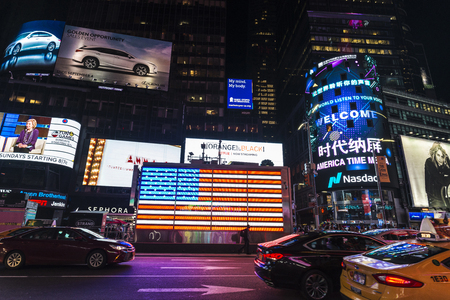 New York City, USA - July 30, 2018: Times Square at night with people around and large advertising screens and a flag in Manhattan in New York City, USAのeditorial素材