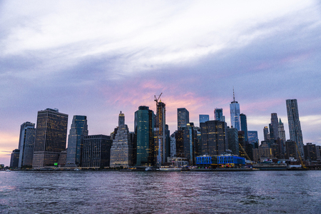 Skyline of modern skyscrapers of New York Financial District and the Lower Manhattan at sunset viewed from the Brooklyn Bridge Park in New York City, USAの写真素材