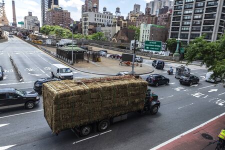 New York City, USA - July 31, 2018: Truck loaded with straw bales circulating on a street in front of Queensboro Bridge in New York City, USAのeditorial素材