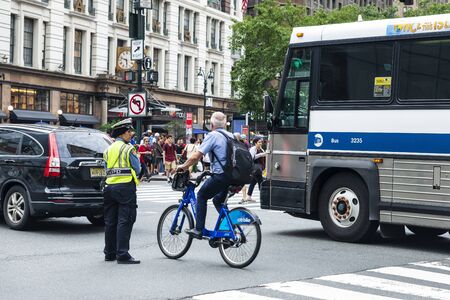 New York City, USA - July 31, 2018: Muslim woman police officer directing traffic on a street while...