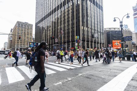 New York City, USA - July 31, 2018: People going through a pedestrian crossing in front of the...