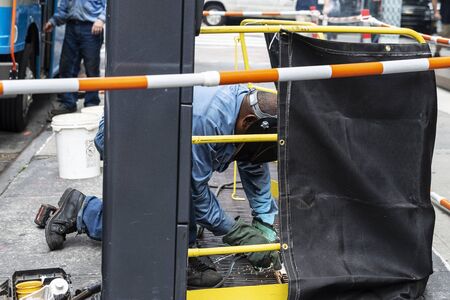 Welder doing a welding with goggles on a street in Manhattan, New York City, USA