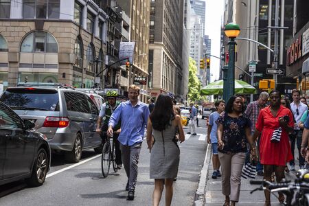 New York City, USA - August 2, 2018: Diversity people walking and a cyclist on a street in...