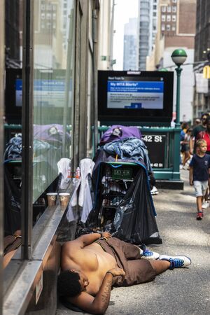 New York City, USA - August 2, 2018: Poor young man lying on the floor half-naked sleeping on a...
