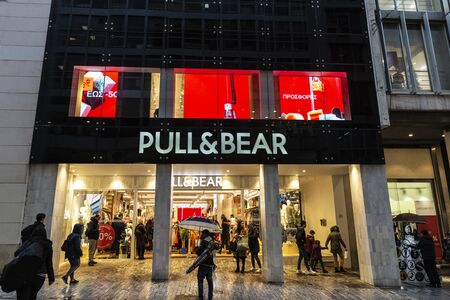 Athens, Greece - January 4, 2019: Display of a Pull & Bear store at night with people around in...