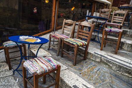 Chairs and tables of a bar on the street stairs in the Plaka neighborhood of Athens, Greece