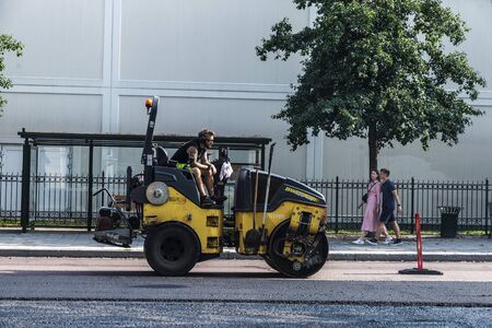 MalmÃ¶, Sweden - August 29, 2019: Worker asphalting a street with a compactor with people around in Malmo, Swedenのeditorial素材