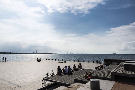 MalmÃ¶, Sweden - August 30, 2019: People sunbathing on the dike in the promenade in front of the...
