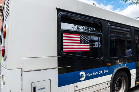 New York City, USA - August 4, 2018: Bus with an american flag and people around drive along in Harlem, Manhattan, New York City, USAのeditorial素材