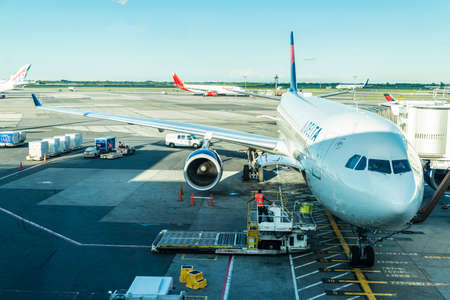 New York City, USA - August 4, 2018: Worker loading and unloading goods in Delta Air Lines airplane parked at John F. Kennedy International Airport (JFK Airport, JFK or Kennedy) in Queens, New York City, USAのeditorial素材