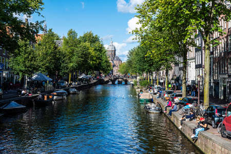 Amsterdam, Netherlands - September 7, 2018: Canal with the Basilica of Saint Nicholas ( Van de Heilige Nicolaas or Sint-Nicolaaskerk) in the background with people around in the old town of Amsterdam, Netherlandsのeditorial素材