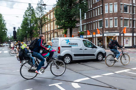 Amsterdam, Netherlands - September 8, 2018: Street with a a father and two children on bicycle in...