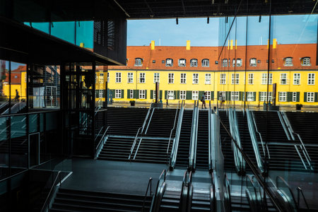 Copenhagen, Denmark - August 27, 2019: Abstraction with escalator, stairs, people, and old houses in...