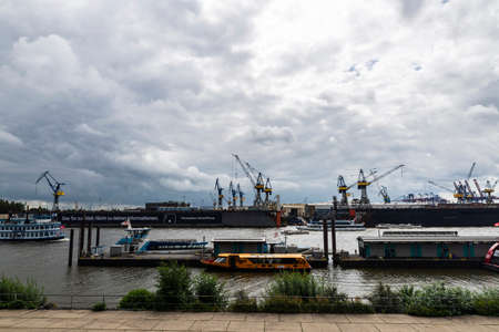 Hamburg, Germany - August 16, 2019: Port of on the Elbe river with cranes, cruise ship and a steamboat with people in Hamburg, Germanyのeditorial素材