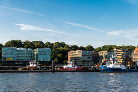Hamburg, Germany - August 22, 2019: Modern buildings and ships moored on the Elbe river in the port...