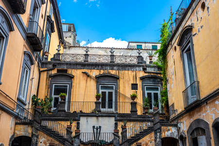 Facade of a classic building or mansion with two stairs and decorated with busts in the historical center of Naples, Italyの写真素材