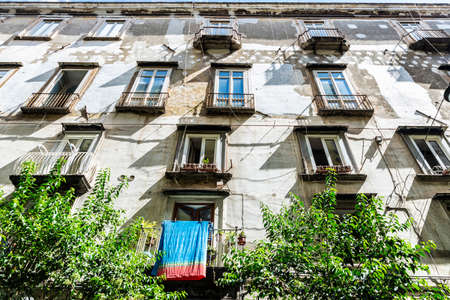 Facade of an old classic building with hanging clothes in the historical center of Naples, Italyの写真素材