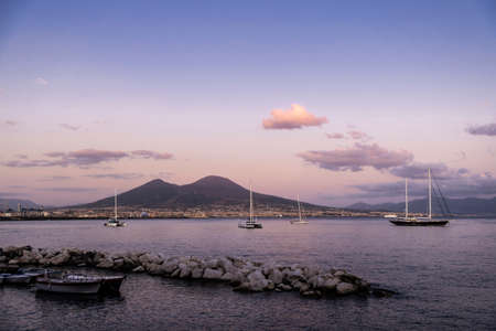 Sailboats, boats and catamarans moored or sailing at sunset on the gulf of Naples in front of the Mount Vesuvius, Italyの写真素材