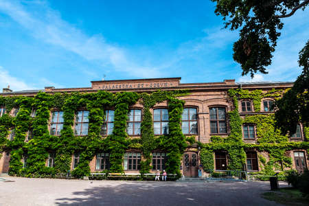 Lund, Sweden - August 30, 2019: Old classic facade with creeping plants of a buiding of the Lund University and people around in Lund, Scania, Swedenのeditorial素材
