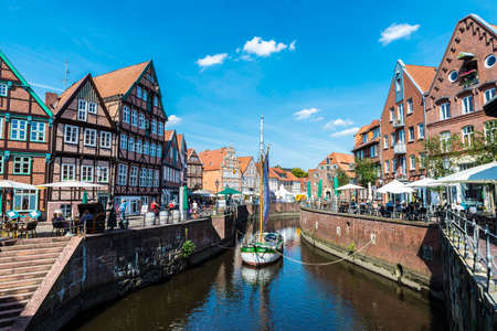 Hansestadt Stade, Germany - August 22, 2019: Old wooden sailboat, medieval houses and restaurants by the canal with people around in the old town of Stade, Lower Saxony, Germanyのeditorial素材