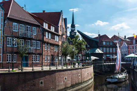 Hansestadt Stade, Germany - August 22, 2019: Old wooden sailboat and medieval houses by the canal with people around in the old town of Stade, Lower Saxony, Germanyのeditorial素材