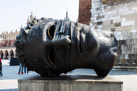 Krakow, Poland - August 28, 2018: Eros Bendato or Eros bound, giant head bronze statue next to the Rynek Underground Museum in the Main Market Square with people around in Krakow, Polandのeditorial素材