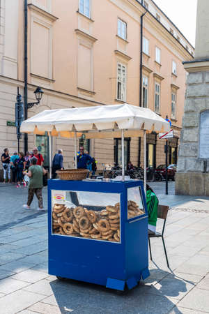 Krakow, Poland - August 28, 2018: Traditional obwarzanek krakowski, braided ring-shaped bread, in a stall on a street with people around in the old town of Krakow, Polandのeditorial素材
