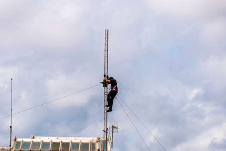Barcelona, Spain - October 1, 2021: Construction worker disassembling an antenna on the roof of a residential building in Barcelona, Spainのeditorial素材