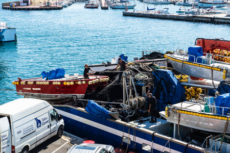 L Ametlla de Mar, Spain - May 11, 2022: Tuna purse seiner ship with workers docked in the port of...