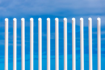 Bars of a white fence against the blue sky as abstract backgroundの写真素材