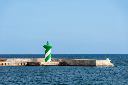 Lighthouse on a breakwater or seawall in the port of Barcelona in Catalonia, Spainの写真素材