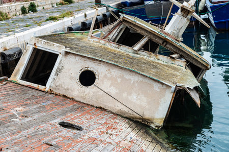 Old abandoned and sunken wooden fishing boat in the port of Sciacca, fishing village in Sicily, Italyの写真素材