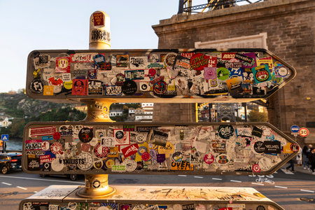 Porto, Portugal - November 24, 2023: Collage of advertising stickers on three arrow shaped traffic indicators in Porto or Porto, Portugalのeditorial素材