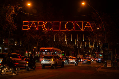Barcelona, Spain - November 25, 2025: Christmas lights decoration hanging on the street illuminated at night with traffic and Barcelona sign in Gran Via, Catalonia, Spainのeditorial素材
