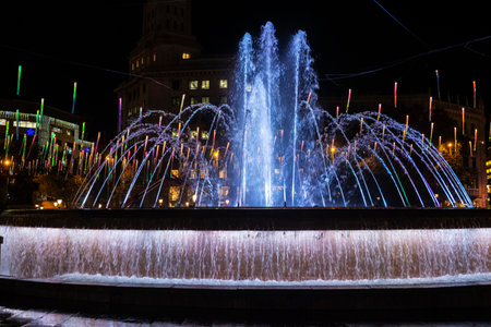 Christmas lights decoration hanging on the street illuminated at night and fountain in Catalonia square, Barcelona, Catalonia, Spainの写真素材