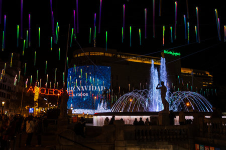 Barcelona, Spain - November 25, 2025: Christmas lights decoration hanging on the street illuminated at night and fountain with people around in Catalonia square, Barcelona, Catalonia, Spainのeditorial素材