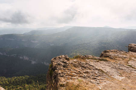 rocky cliff landscape of La Mussara, Tarragona, with views of mountains, forests, fog and cloudy skyの写真素材