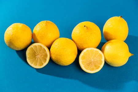 group of six yellow lemons (fruit) and two halves. blue background. studio photo.の写真素材
