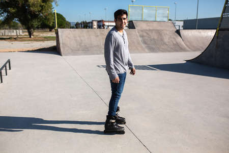 roller skater boy in a skate park posing for a face photo for the session. with t-shirt and jeans