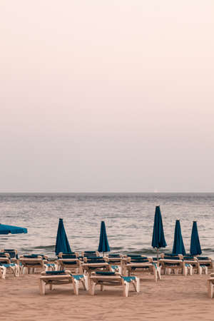 benidorm beach empty, no people. with hammocks and parasols, cloudy day. pandemic, coronavirusの写真素材